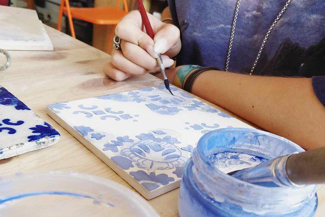 Un artista dipinge manualmente un azulejo.